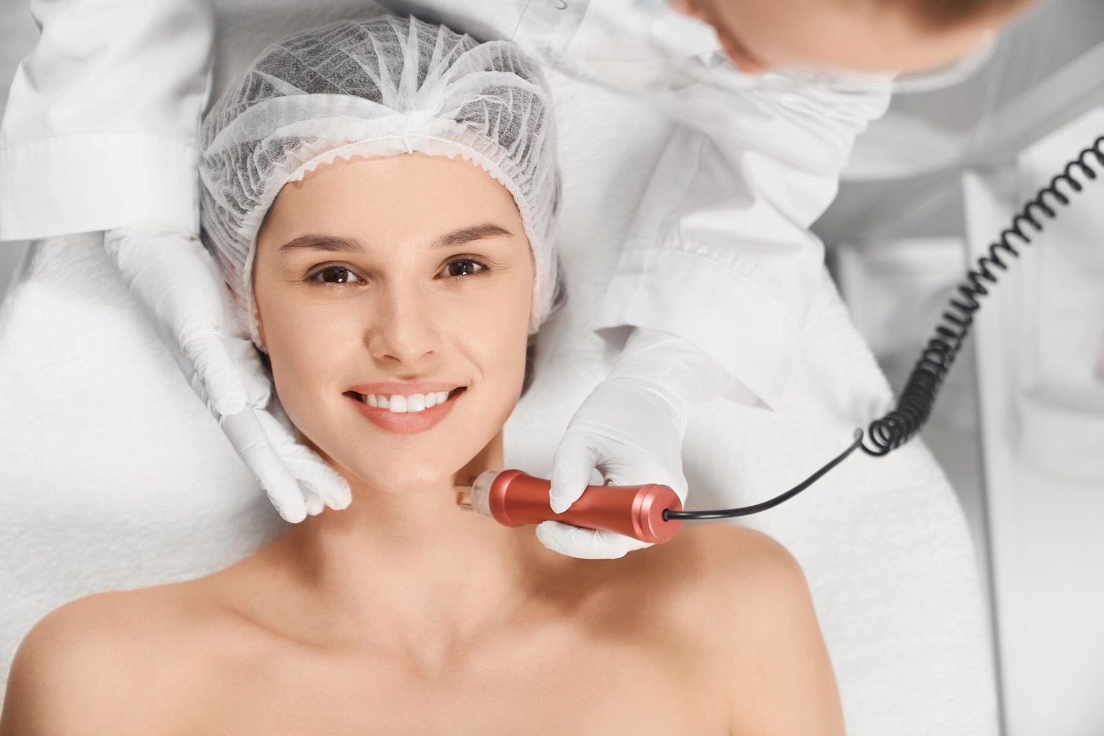 Top view portrait of smiling attractive woman in beautician on procedure for face with special equipment. Concept of beauty procedure anti-aging and improvements skin.